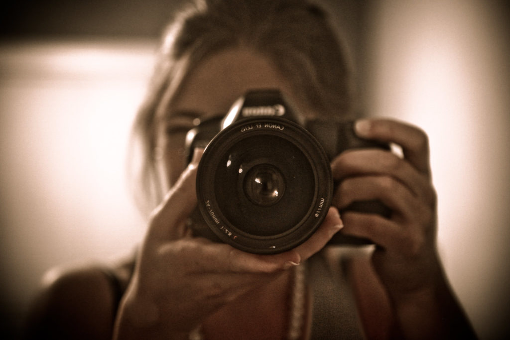 Una chica sujeta una camara frente a un espejo,